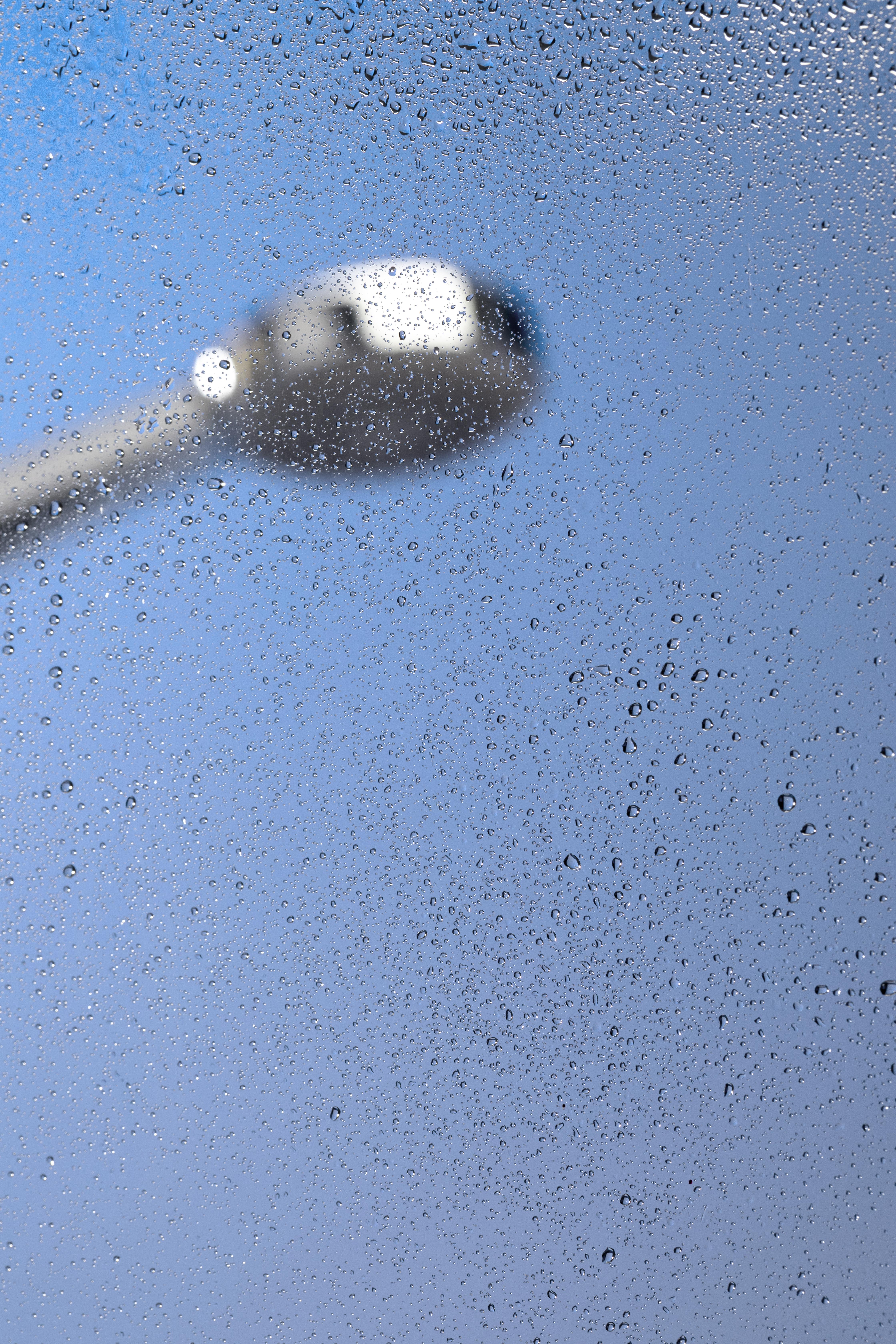 Pommeau de douche sur une parroie vitrée de salle de bains