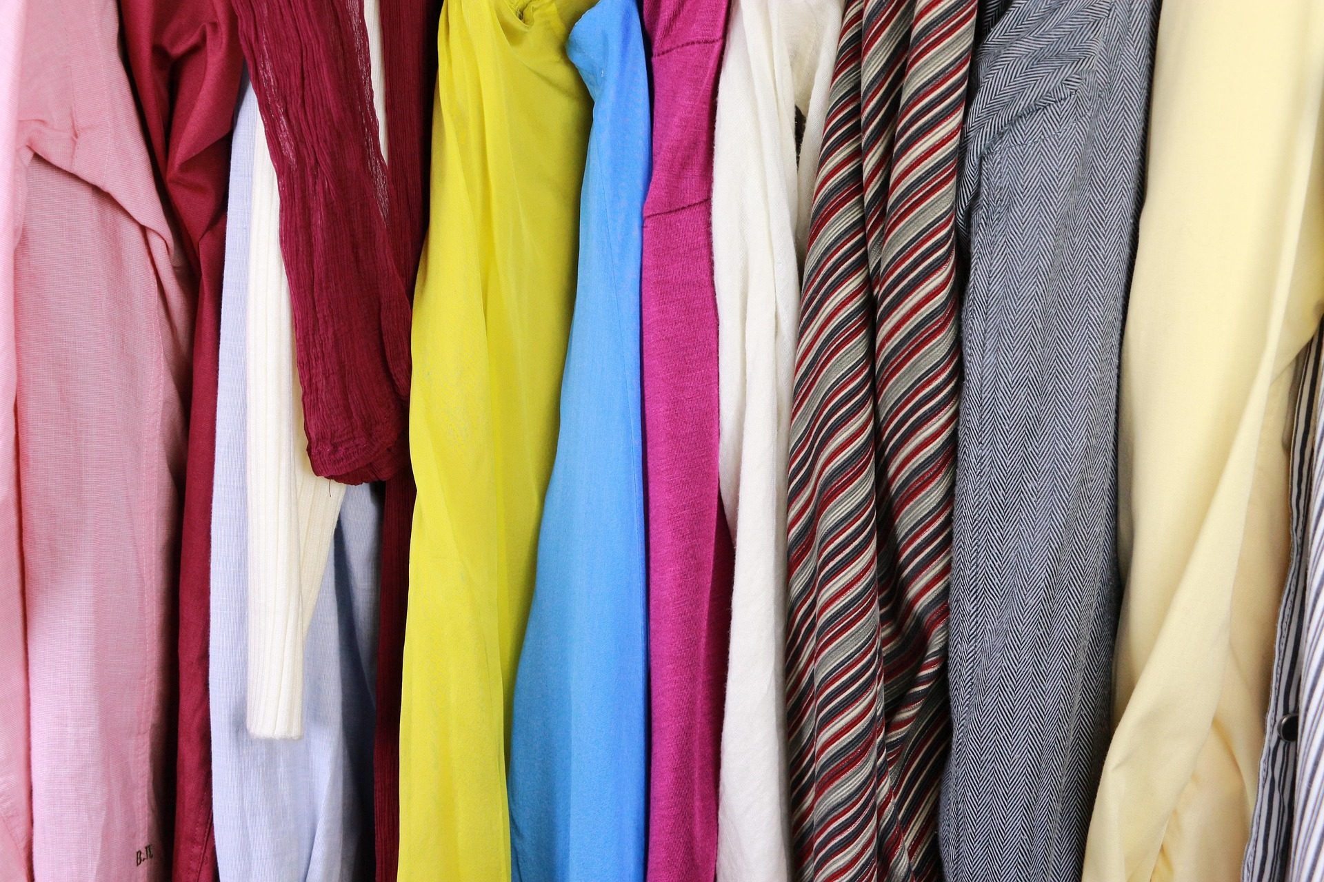 Vêtements suspendus sur des cintres dans une penderie, illustrant l'importance de choisir un cintre adapté à chaque type de textile.